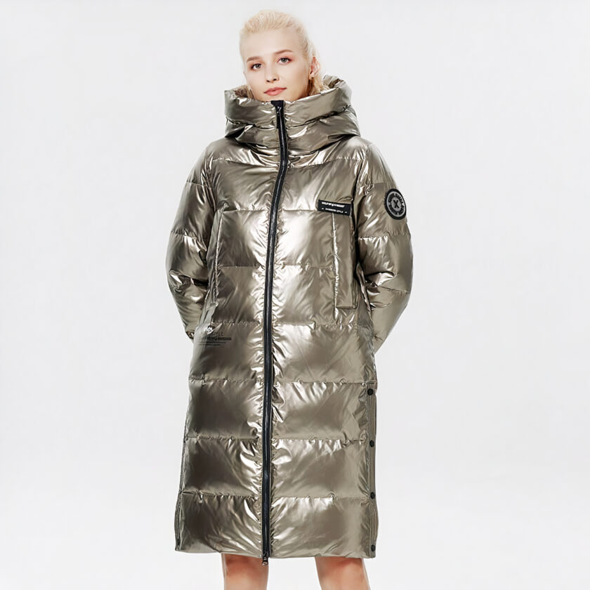 Donna che indossa un lungo piumino dorato su uno sfondo grigio.