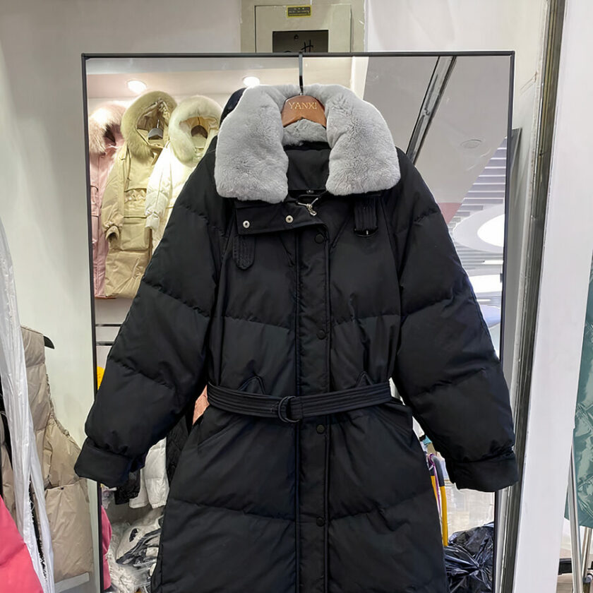 Piumino nero trapuntato con collo in pelliccia grigia e cintura in vita.