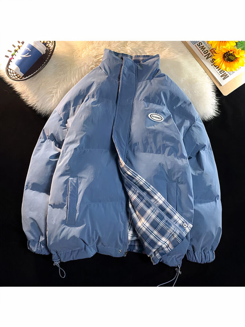 La foto è scattata dall'alto: mostra un piumino reversibile blu con un motivo a quadri blu. È posizionato su un tappeto di finta pelle di pecora.