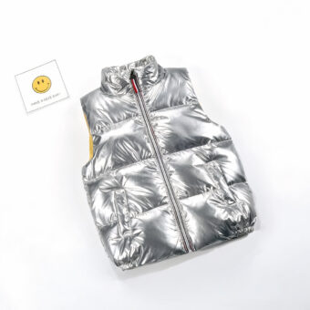 Foto di un piumino argentato senza maniche per bambini con accanto una faccina sorridente.
