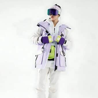 Donna in tenuta da sci con giacca da sci viola, cappello viola e occhiali da sci viola.