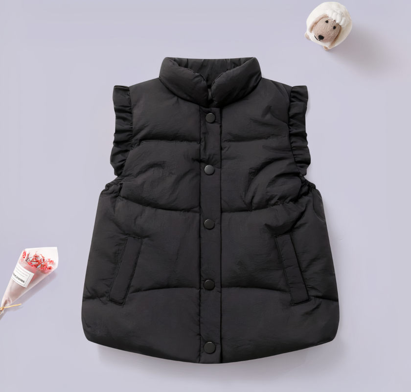 Vediamo un grazioso piumino nero senza maniche per una bambina. È presentato su uno sfondo viola.