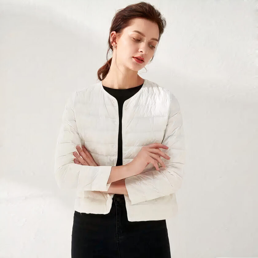 Donna che indossa un piumino bianco e incrocia le braccia, sfondo bianco.