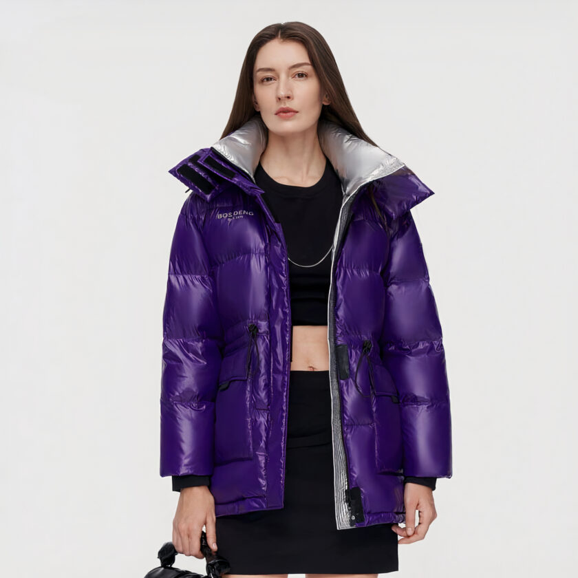 Donna dai capelli scuri che indossa un piumino viola aperto con abiti neri sotto.