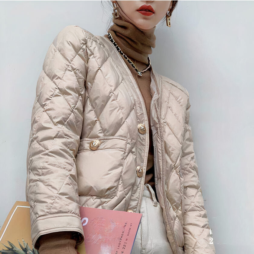 Donna che indossa un piumino beige corto, sottile ed elegante con un dolcevita marrone e una rivista.