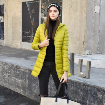 Donna per strada che indossa un piumino giallo con cappello e borsetta beige