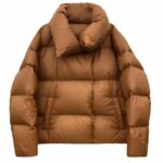 Piumino da donna trapuntato con collo alto e due tasche laterali. Colore cammello su sfondo bianco.