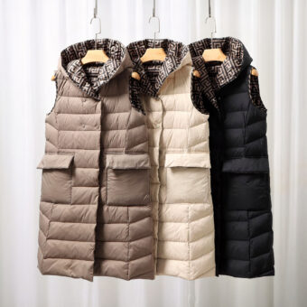 Piumini lunghi e sottili senza maniche di colore marrone, bianco e nero su uno scaffale.