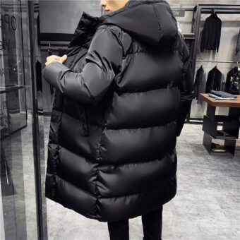 Uomo di spalle in un negozio di abbigliamento grigio che indossa un parka nero con cappuccio di media lunghezza.