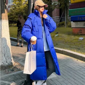 Foto di una donna che indossa un lungo piumino blu per strada