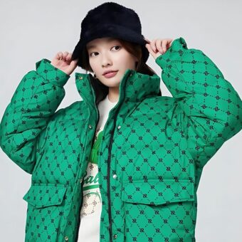 Una giovane donna indossa un piumino oversize, extra caldo, a collo alto e senza cappuccio, di colore verde brillante.