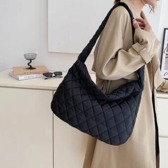 vediamo una donna con un cappotto beige che porta una borsetta doudoune per donna nera